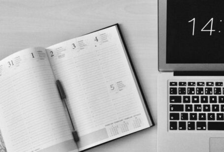 Clock Computer - Flat Lay Photography of Unfold Book Beside Macbook