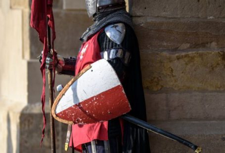 Security Shield - Man Wearing Gray and Red Armour Standing on the Streets