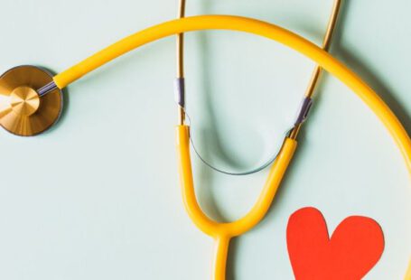 Diagnostic Tool - Medical stethoscope with red paper heart on white surface