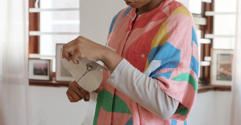 Manual Book - Concentrated female designer preparing paper cutouts for creative project