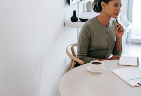 Task Manager - Concentrated ethnic female HR interviewer or psychologist in formal clothes sitting at round table with pen and notepad while looking away in contemplation