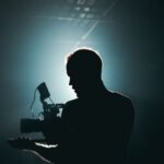 Settings Gear - Silhouette of Man Standing in Front of Microphone