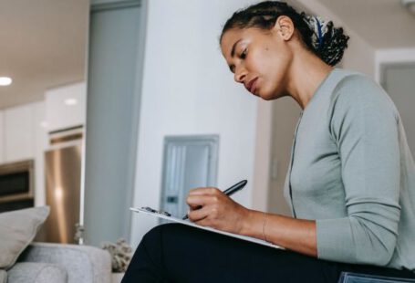 Task Manager - Concentrated ethnic female interviewer or psychotherapist taking notes in clipboard