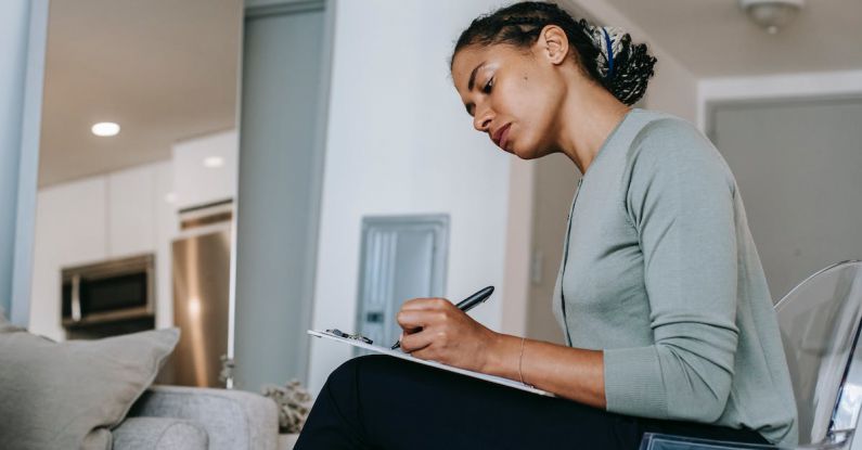 Task Manager - Concentrated ethnic female interviewer or psychotherapist taking notes in clipboard