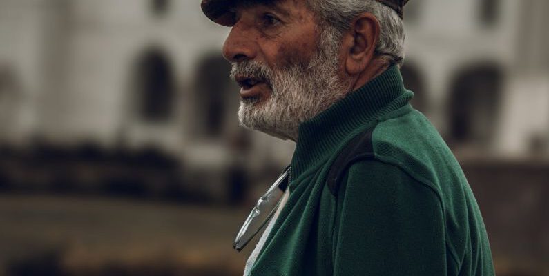 Profile Avatar - Profile of a Senior Man Wearing a Hat, against a Mosque