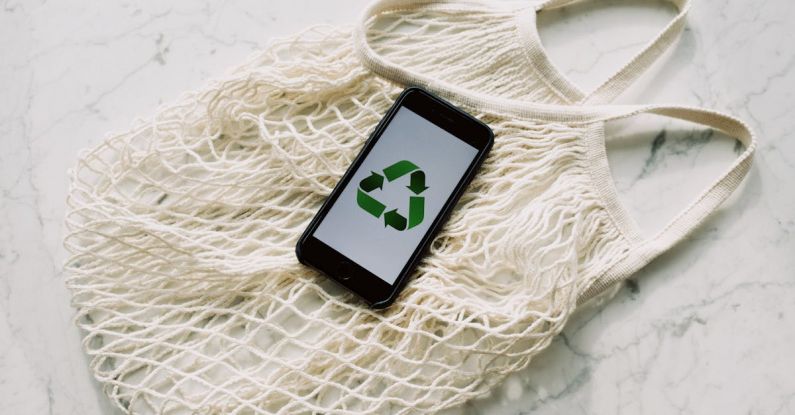 Save Icon - Overhead of smartphone with simple recycling sign on screen placed on white eco friendly mesh bag on marble table in room